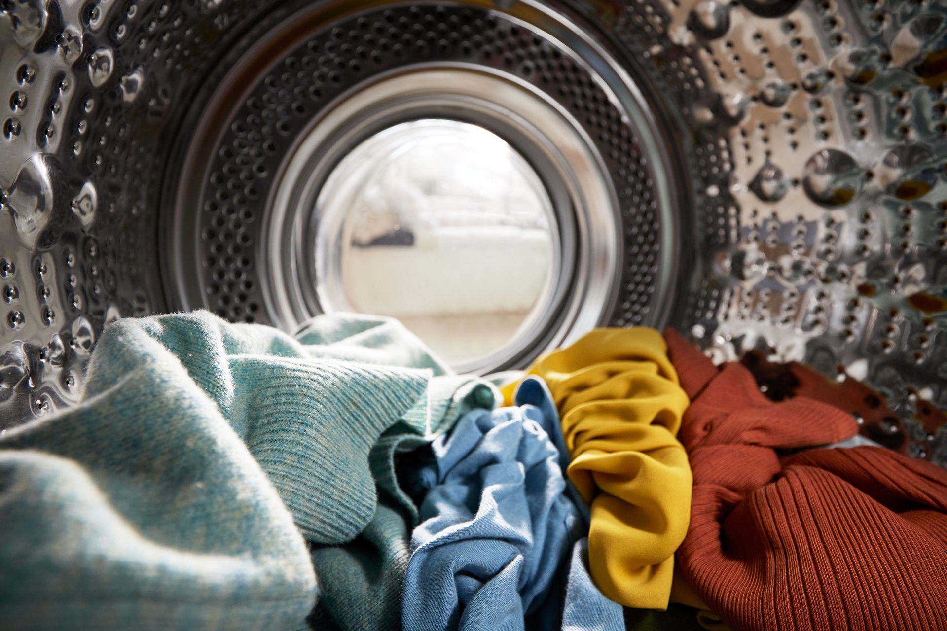 Clothes in washing machine drum, showcasing various colors and textures, illustrating potential for color bleed during laundry.